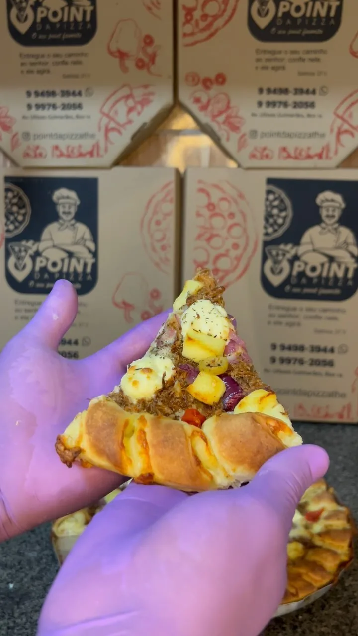 Fatia de pizza segurada na mão sobre caixas com a marca Point